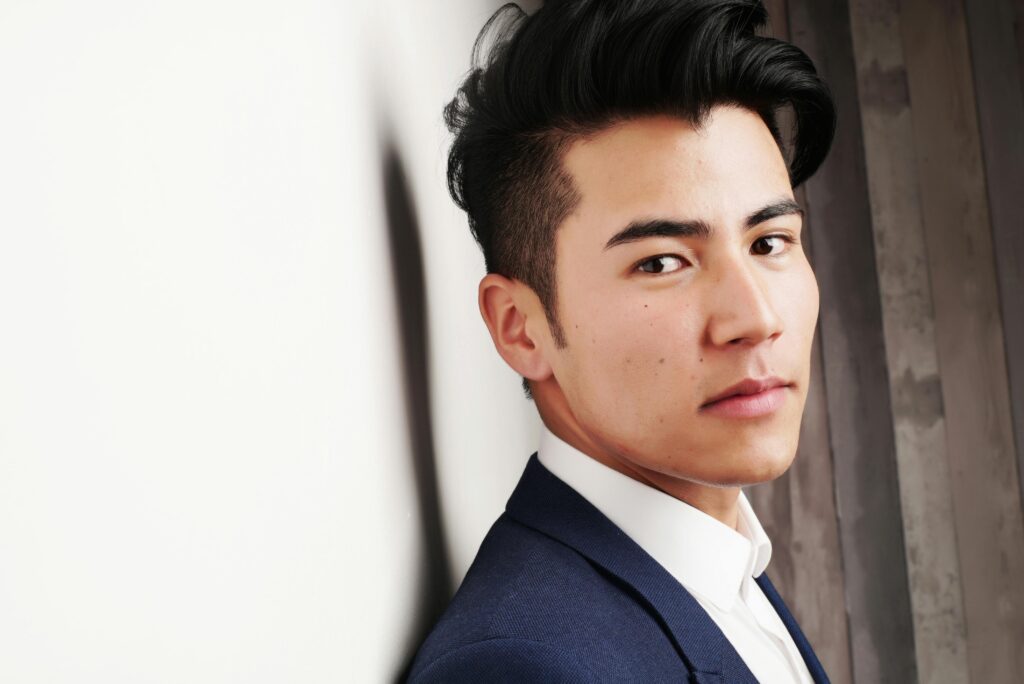 Close-up portrait of a serious Asian man in a formal suit indoors. Modern and professional look.